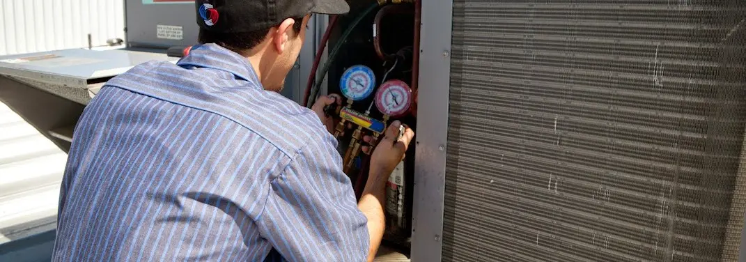 HVAC technician servicing a condenser unit in Tupelo